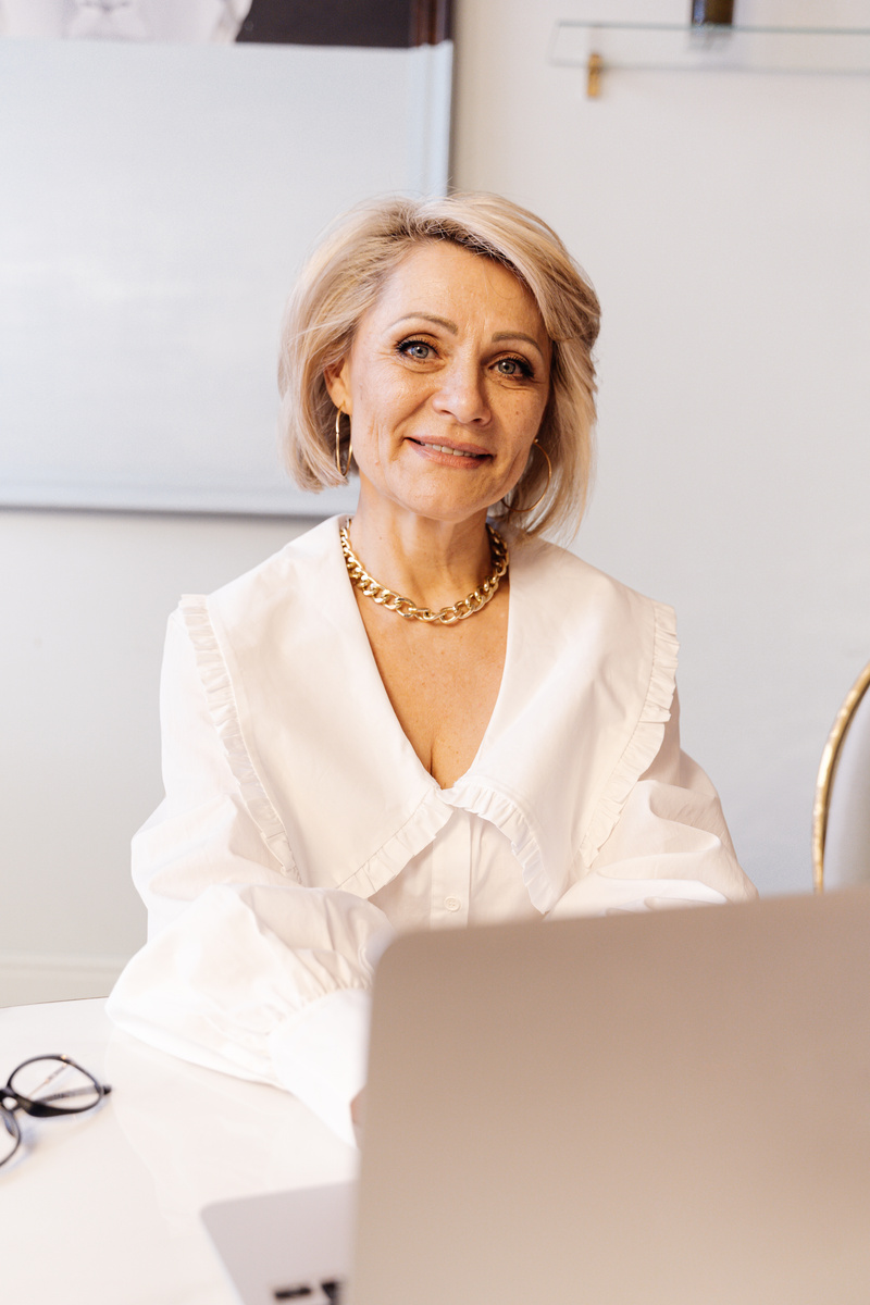 Photo of an Elderly Woman with a Gold Chain Necklace Looking at the Camera